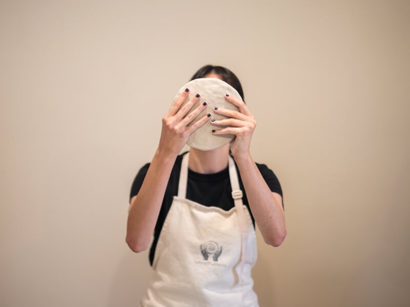 woman holding up hand building clay